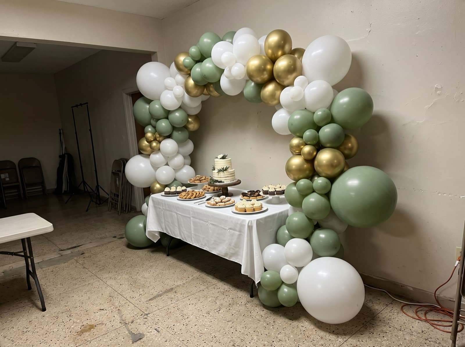 Organic balloon arch in white, sage and gold over a dessert table